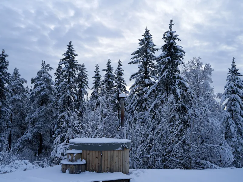 Rustic wooden tub outdoors in a snowy forest