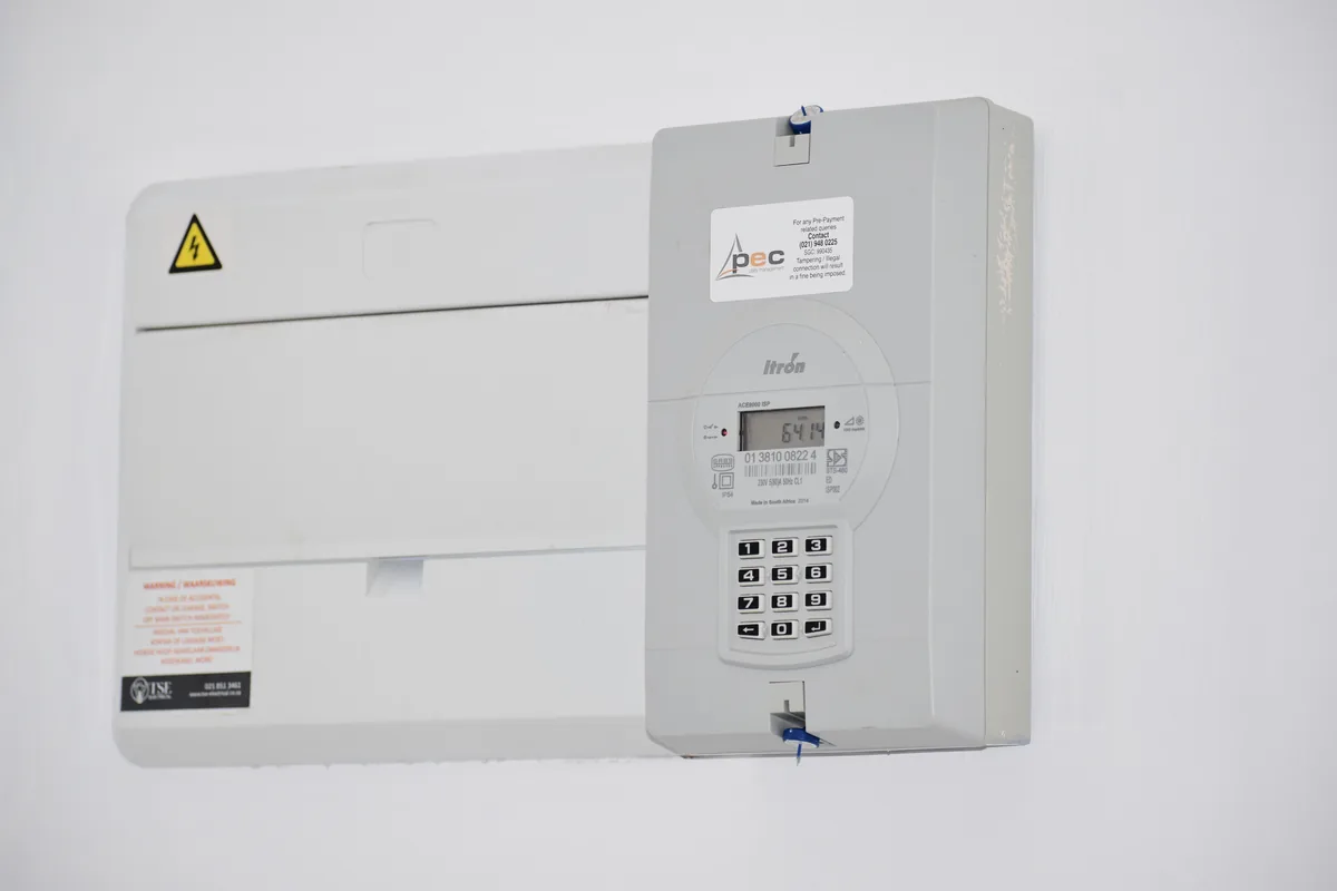 Home electricity meter and consumer unit mounted side by side on a light wall